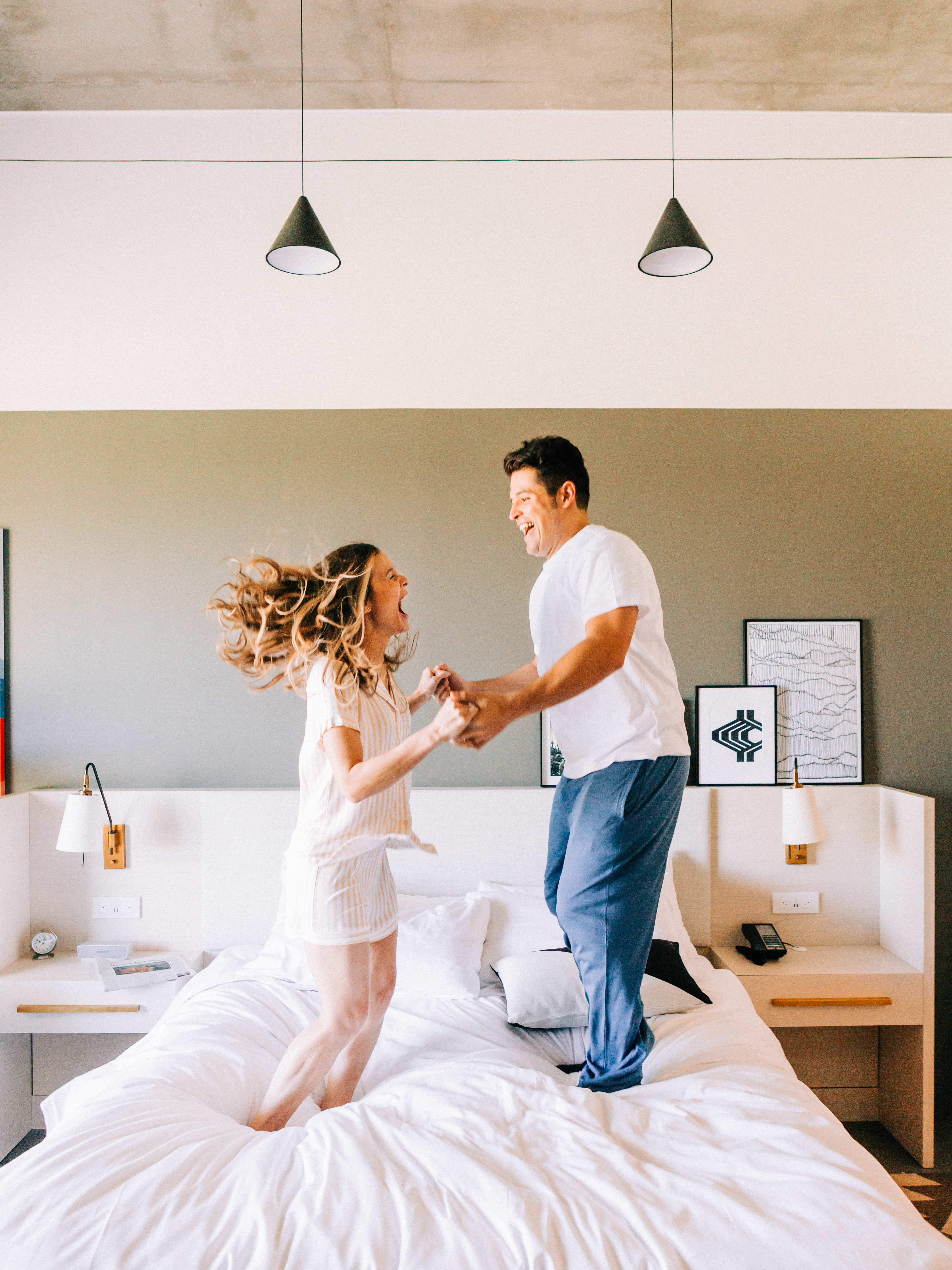 nourish your relationship with positivity - couple laughing and jumping on the bed together 